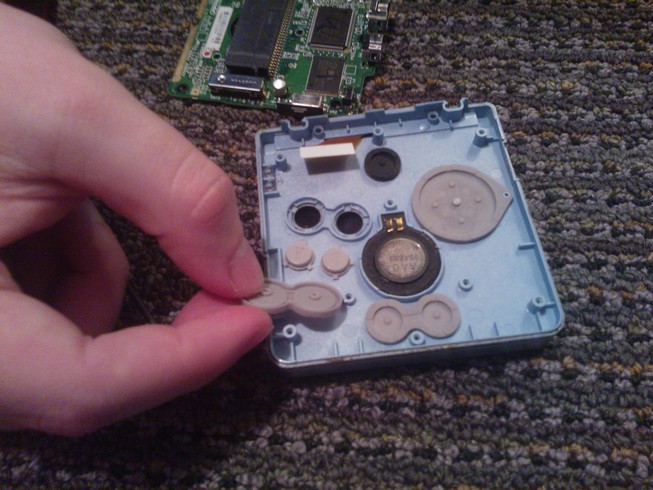 The A and B buttons next to their sockets with the silicon cover in
				hand
