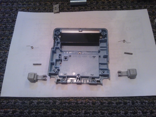 The bottom case with both shoulder buttons removed and all the pieces
				of each on either side