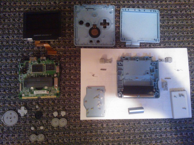 A completely disassembled Gameboy Advance SP with all of the parts
				laid out